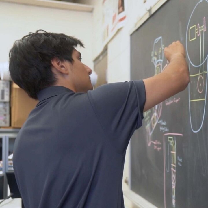 student writing on chalkboard